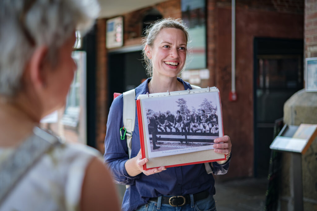 Eine Stadtführerin zeigt den Teilnehmden der Stadtführung historisches Bildmaterial.