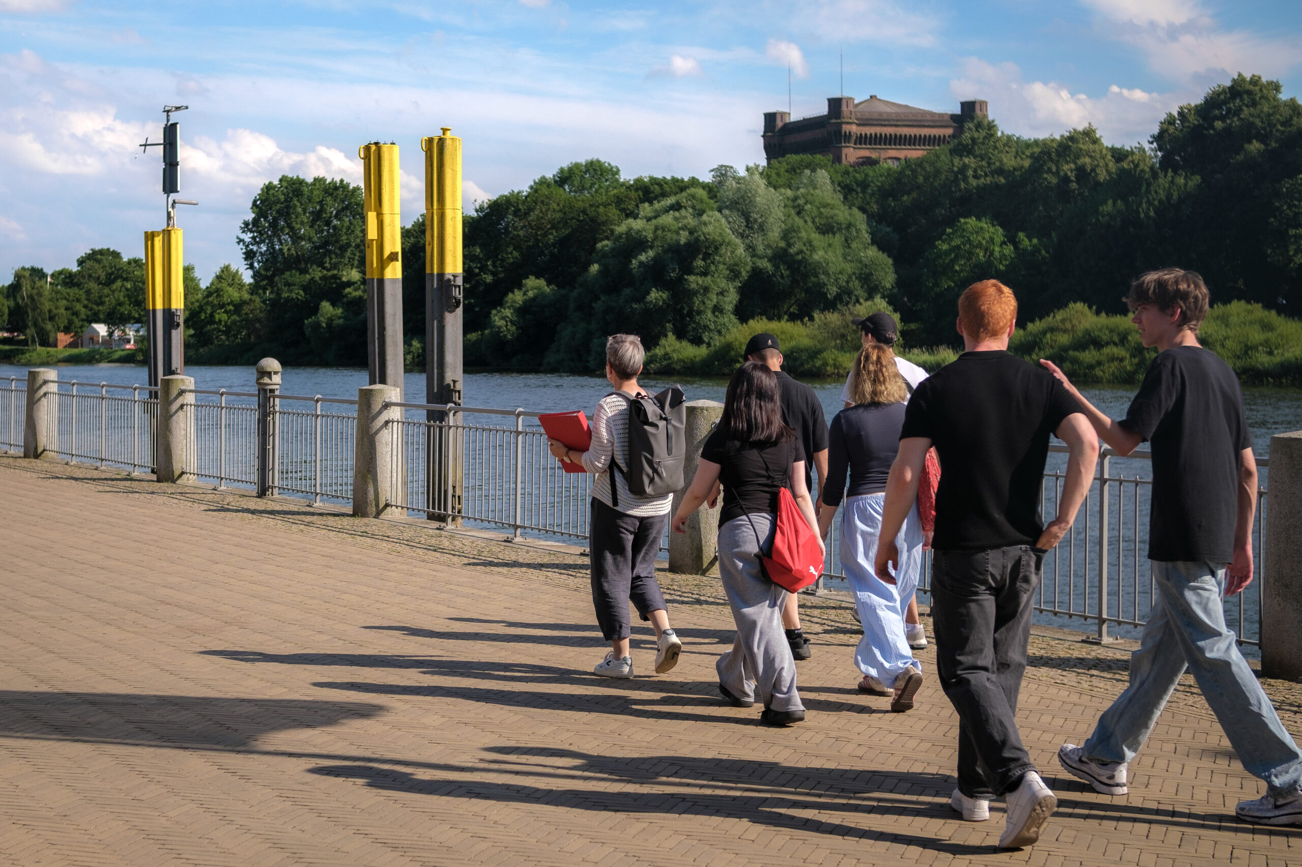 Eine Gruppe geht auf einer Stadtführung entlang der Weserpromenade Schlachte.